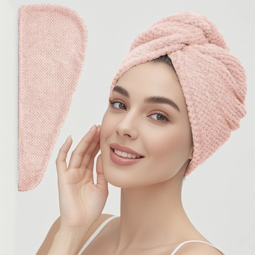 Woman wearing a pink textured towel on her head with a matching pink towel hanging on a wall.
