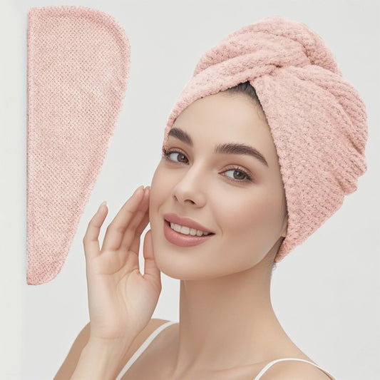 Woman wearing a pink textured towel on her head with a matching pink towel hanging on a wall.